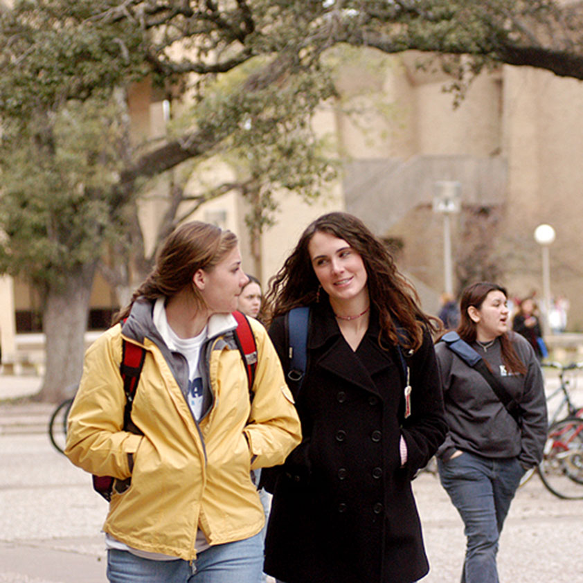 two female students walking in front of the School of Education and Human Development